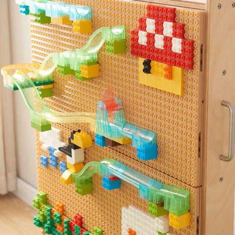 Children exploring colourful STEM wall gears and activities alongside the words Build, Test, Discover.